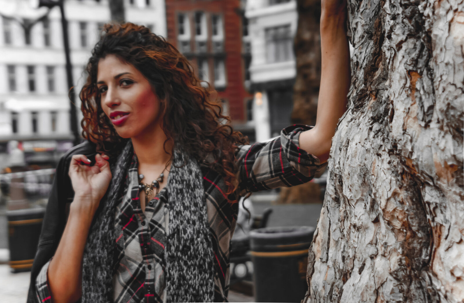 Editorial street portrait of a model with curly hair against a London square, selective-colour grade